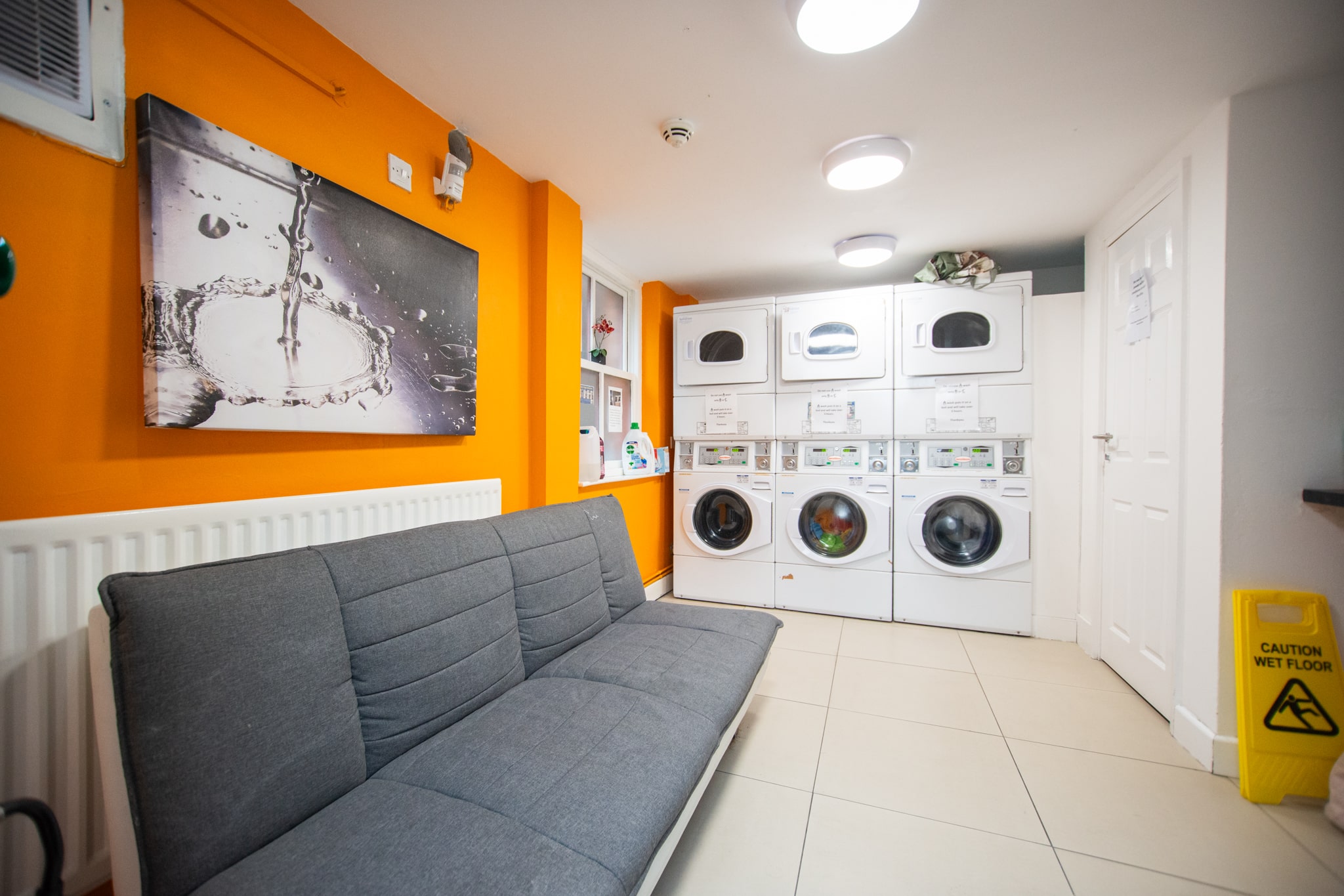 Bedroom with white bed, dark brown runner, wood floor, and modern bathroom with glass door