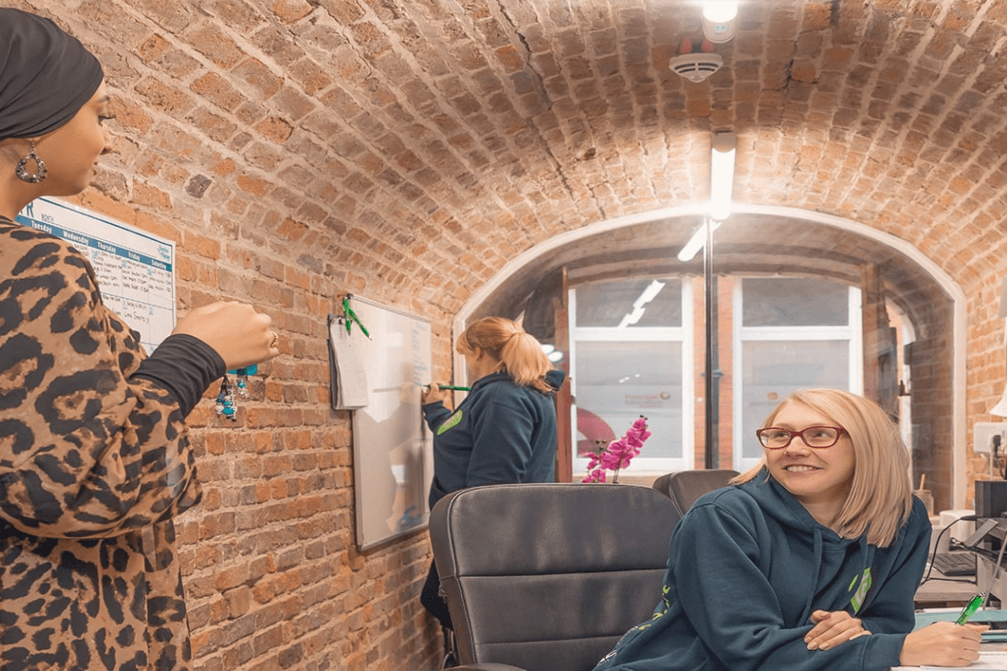 Bedroom with white bed, dark brown runner, wood floor, and modern bathroom with glass door